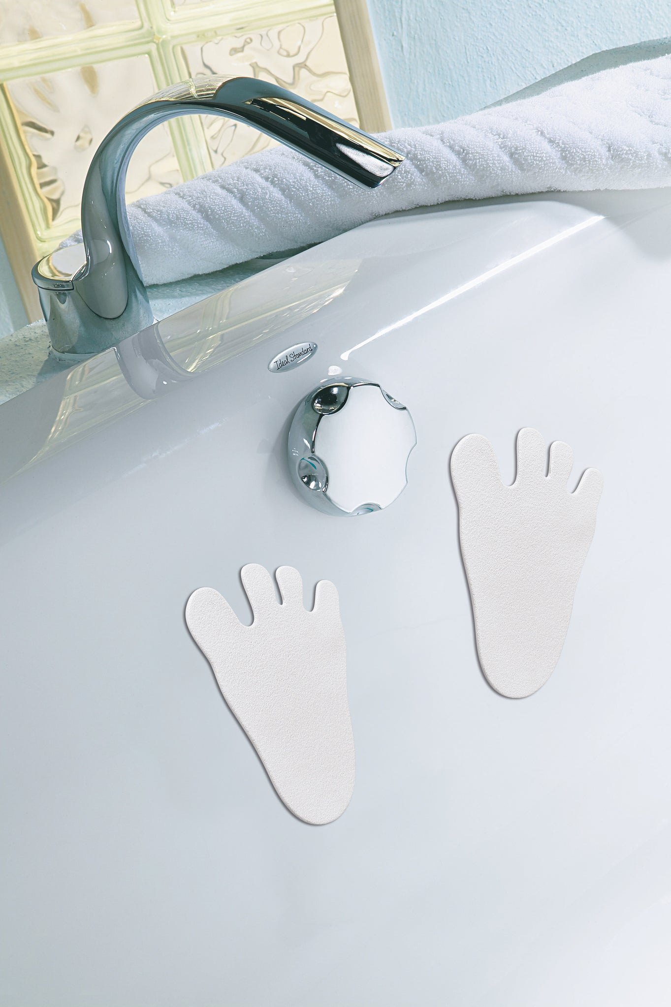 Weiße Fuß-Antirutschaufkleber innen an einer Badewanne mit Armatur
