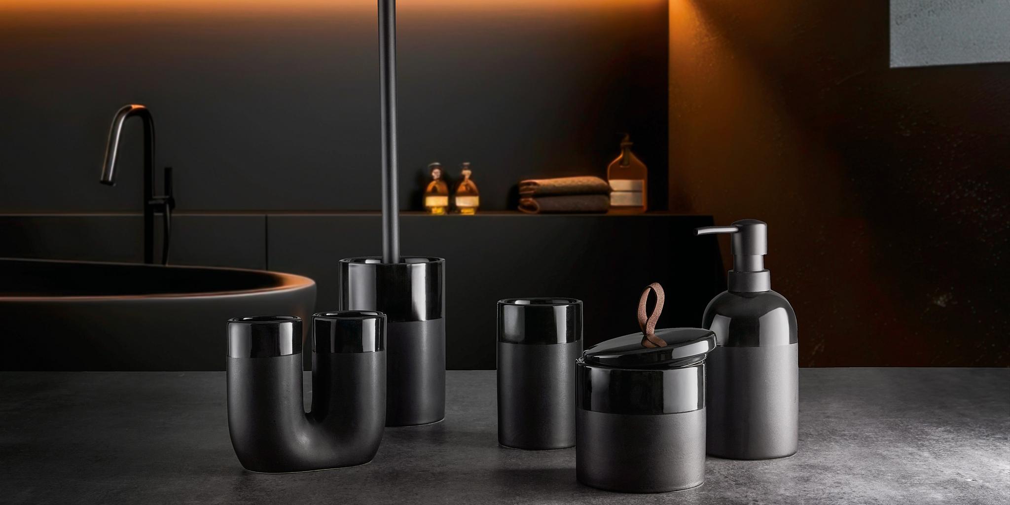 Schwarzes Badaccessoire-Set aus Keramik vor dunkler Waschtischkulisse