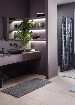 Badezimmer in Anthrazitfarben und Blau eingerichtet mit Badteppich. 