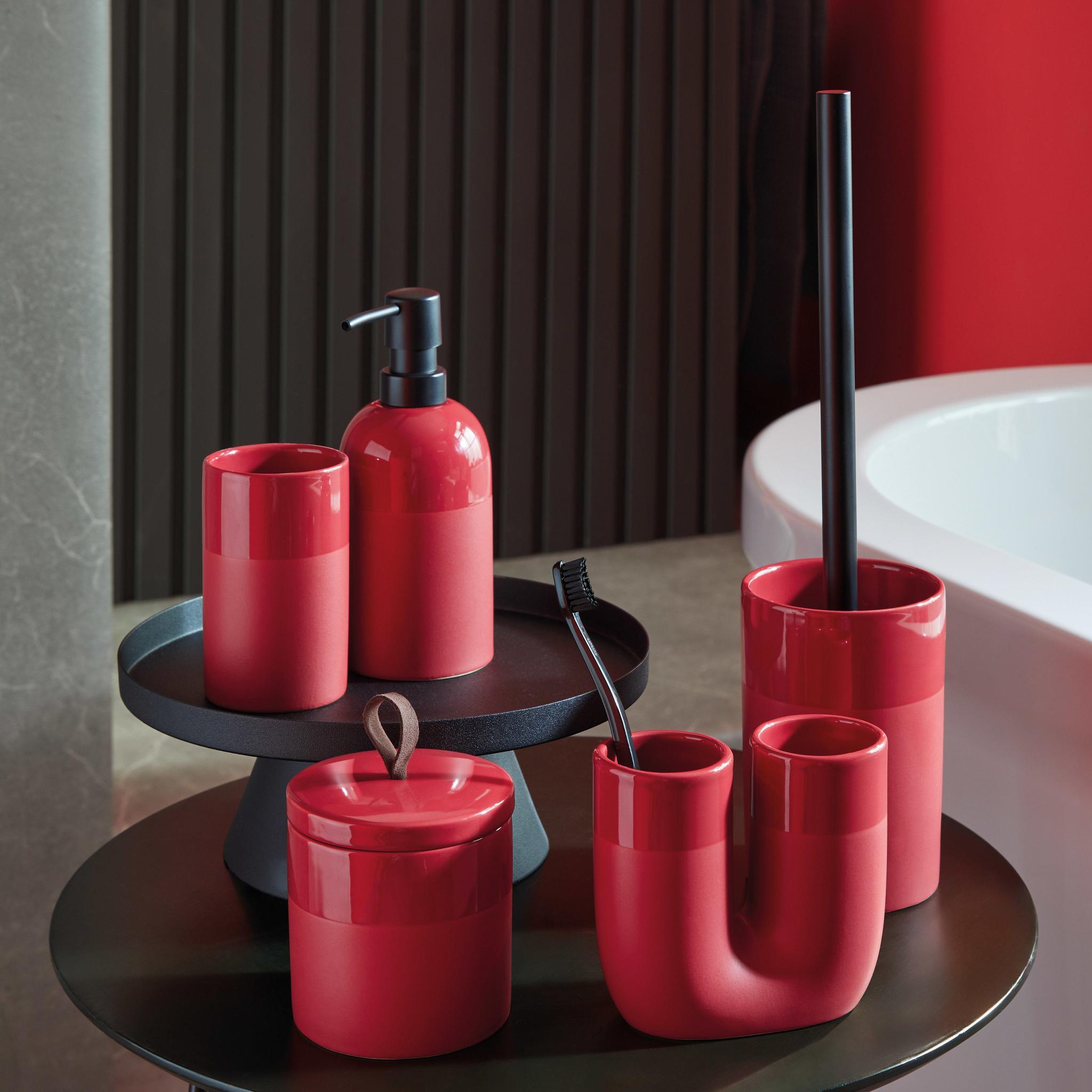 Rotes Badaccessoire-Set aus Bechern, Spender, Behälter und Bürste auf Tisch