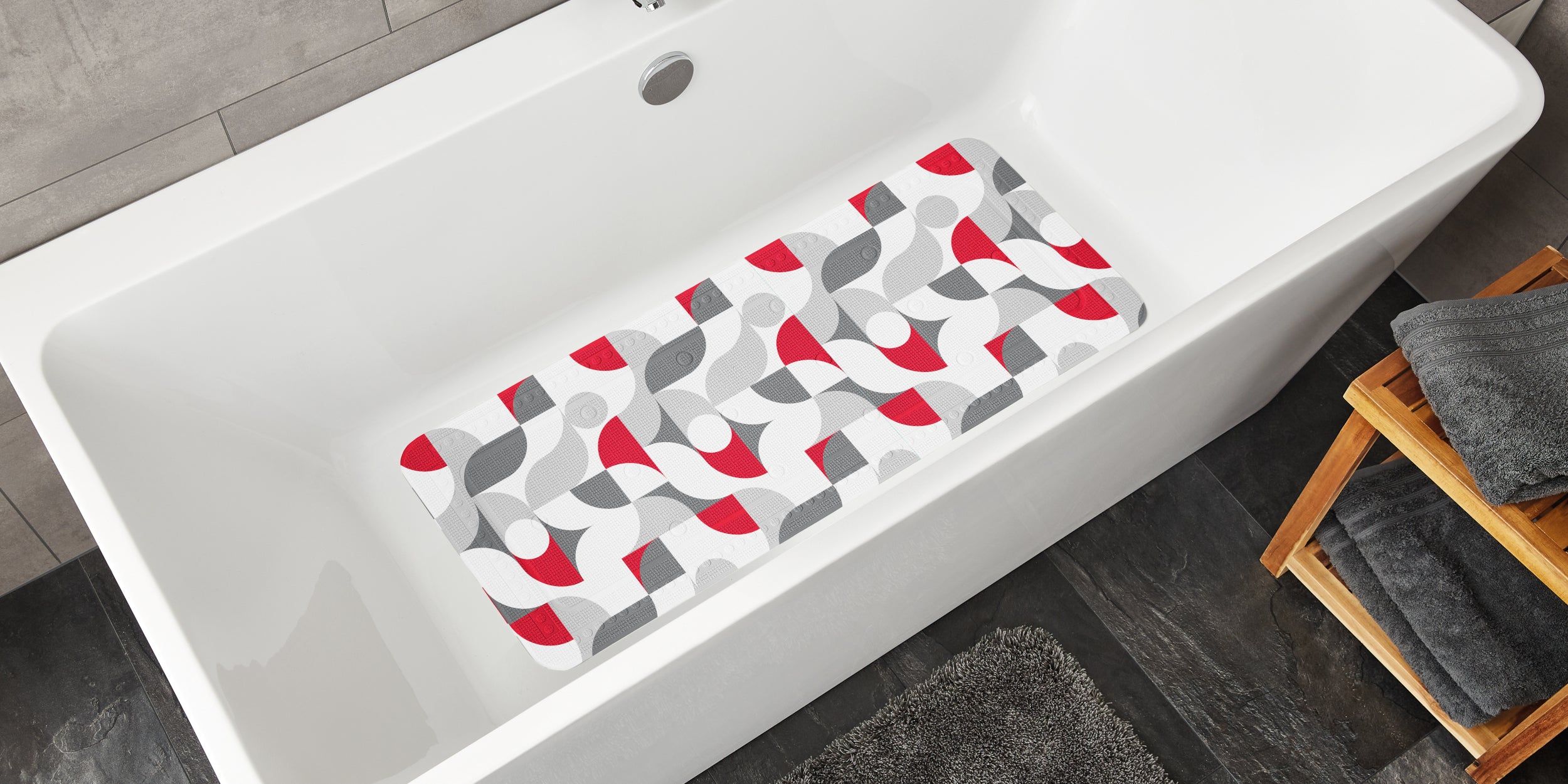 Badewanneneinlage mit rot-grauem Retro-Muster liegt in einer weißen Badewanne.