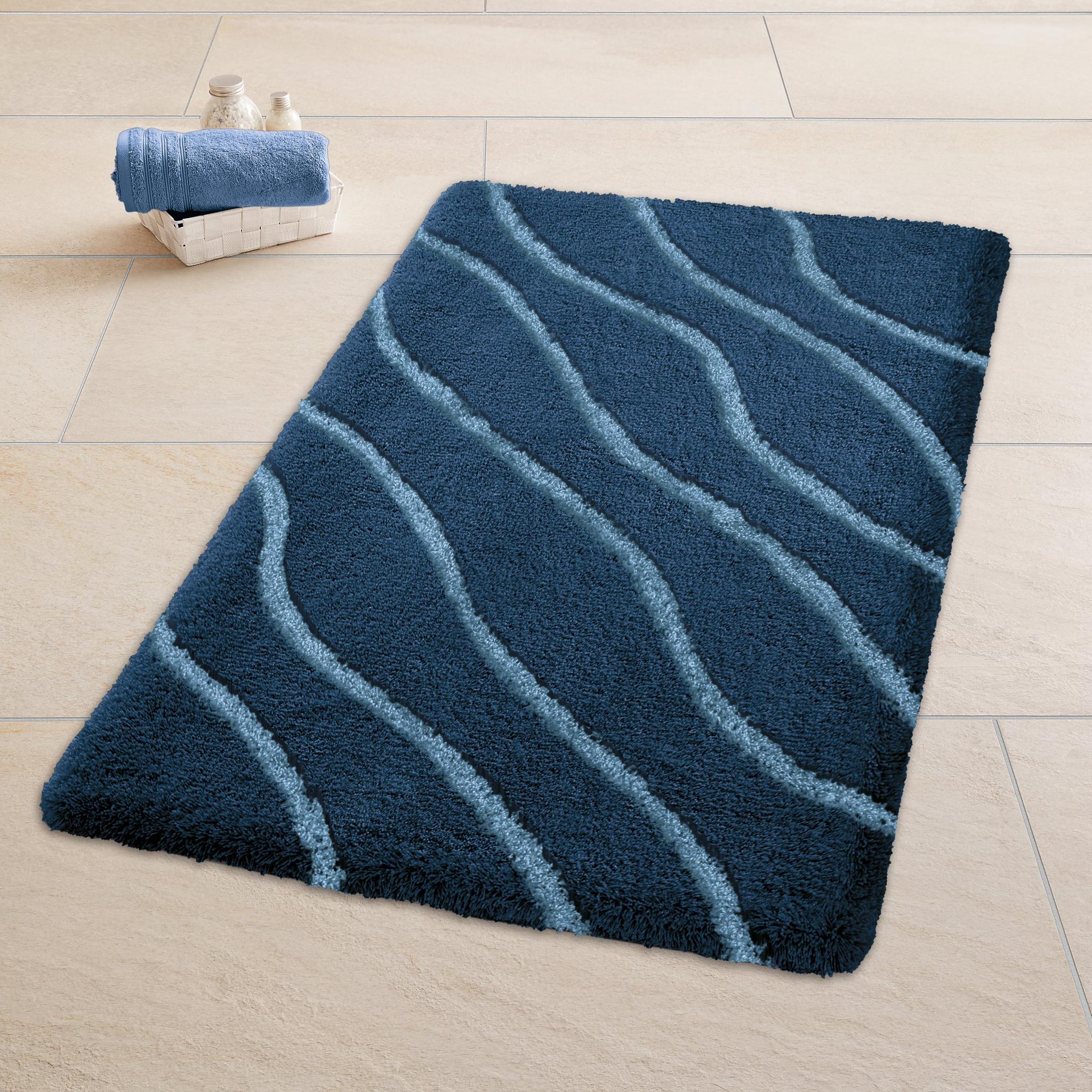 Dunkelblaue Badematte mit hellblauen Wellenlinien auf Fliesenboden