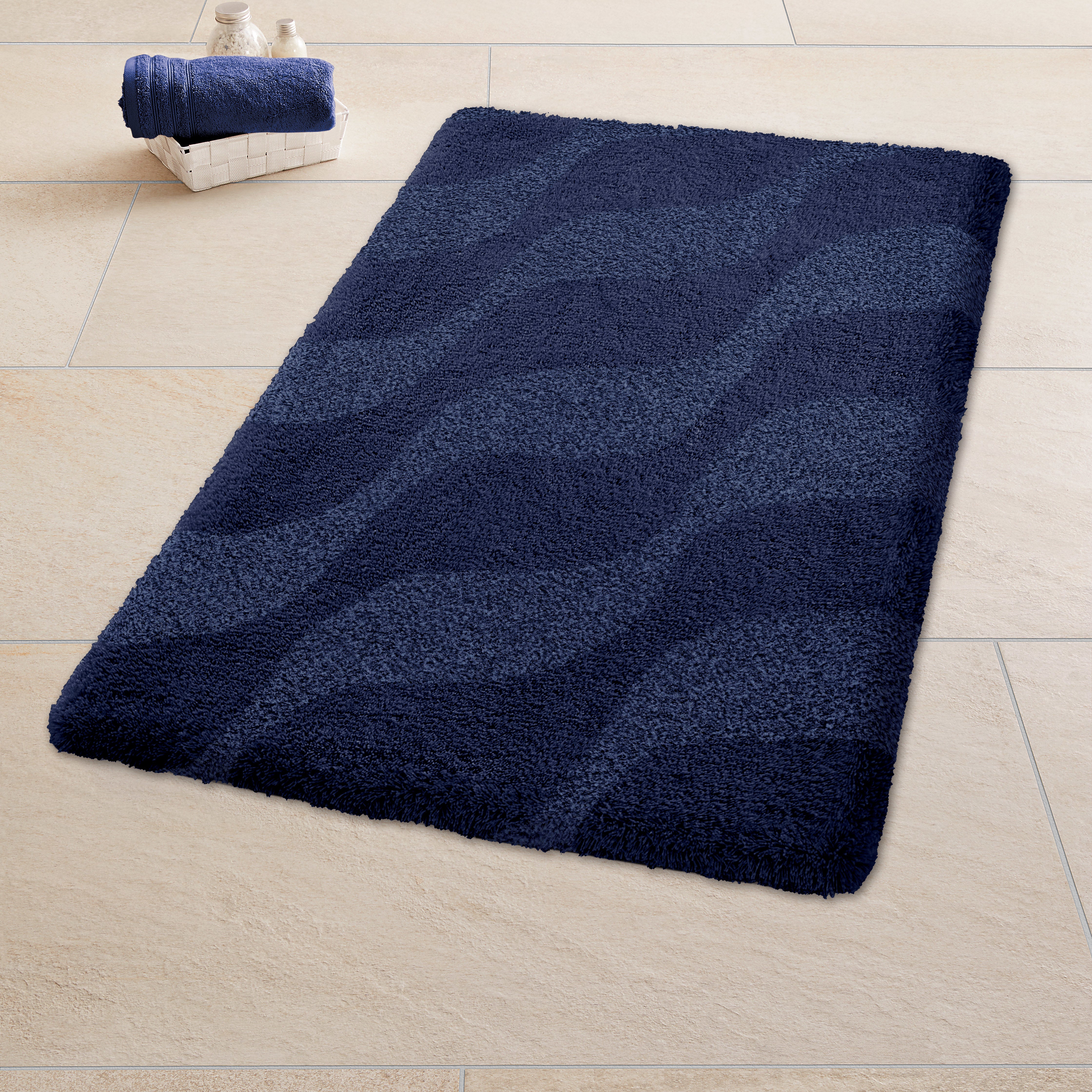 Dunkelblaue Kleine Wolke Badematte Mystic Night Onda mit Wellenmuster auf hellem Fliesenboden im Bad.