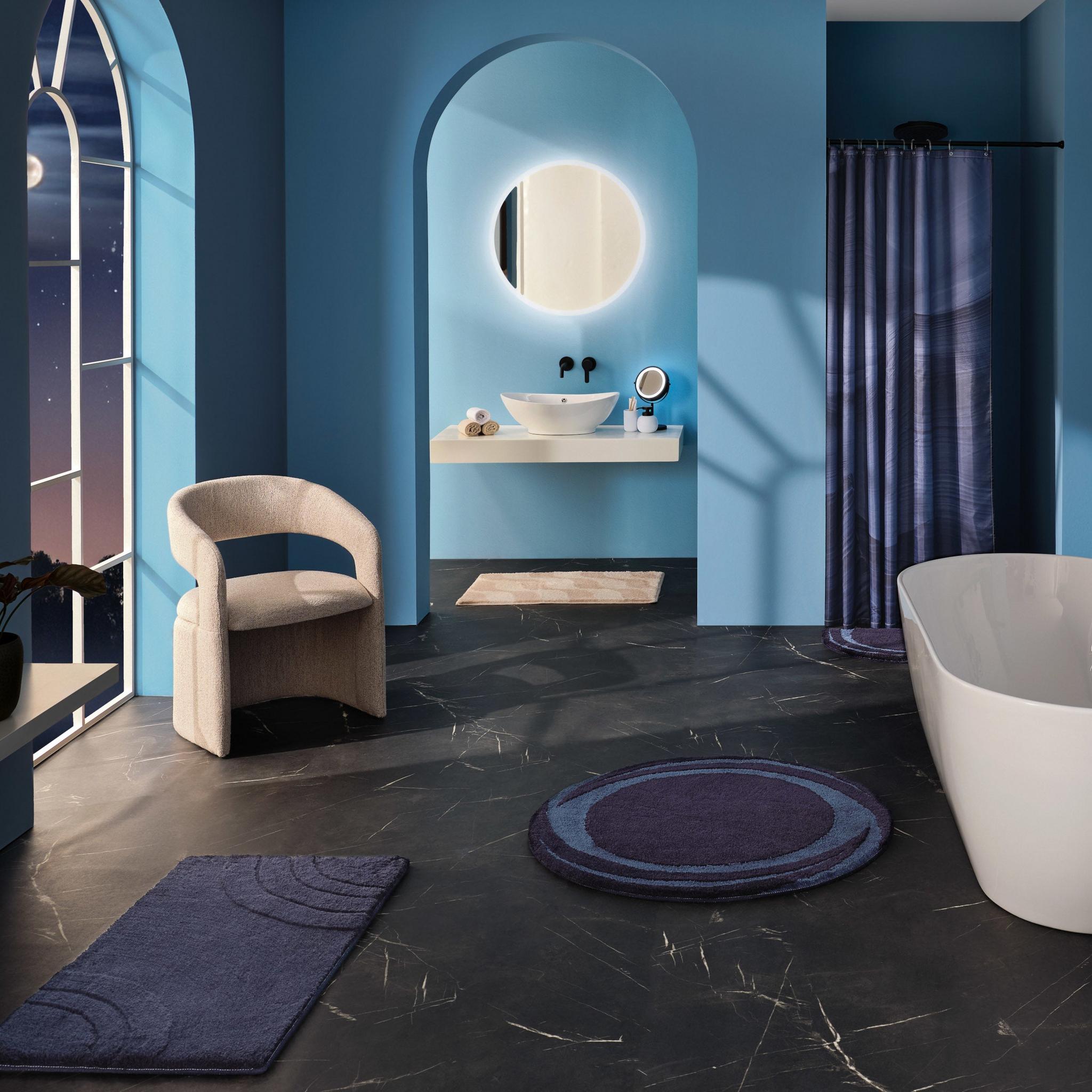 Modernes blaues Bad mit freistehender Wanne und runden Teppichen