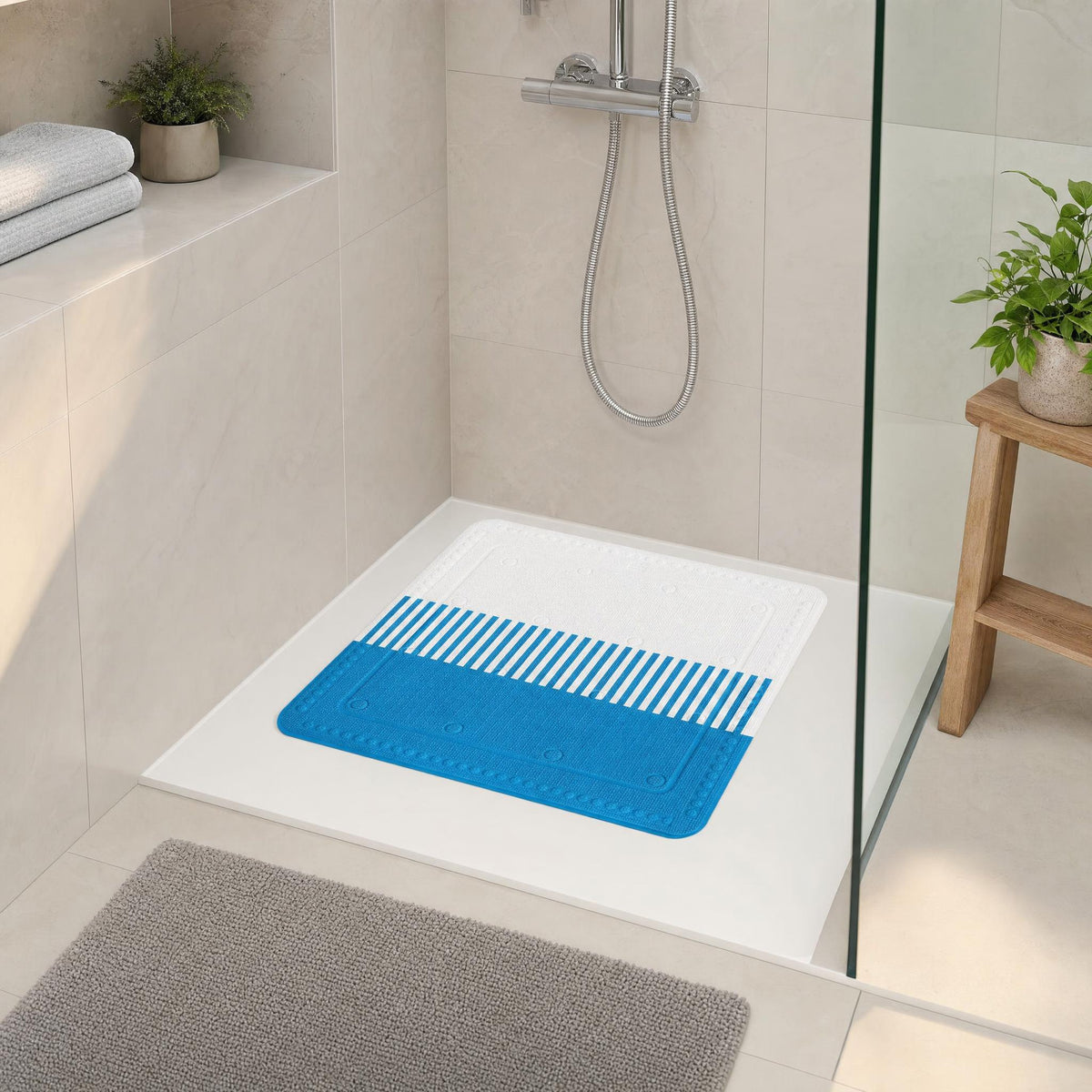 Blaue Duschmatte in moderner, heller Dusche mit Pflanzen und Handtüchern.