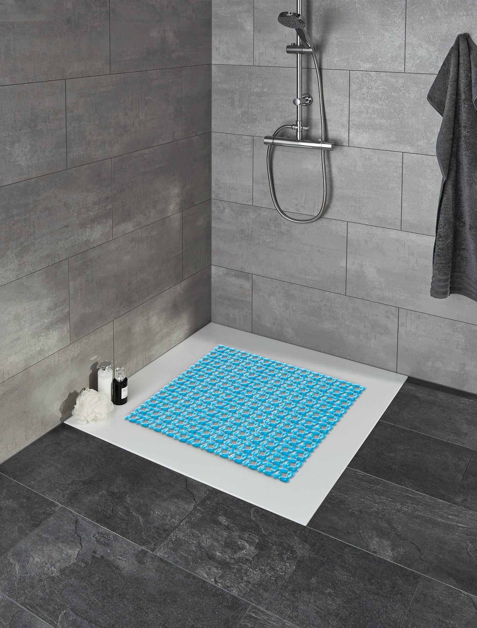 Duscheinlage IVY Türkis liegt in einer modernen, grau gefliesten Dusche auf dem weißen Duschboden.