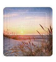 Badematte mit Sonnenuntergang am Strand und Gräsern in den Dünen vorne