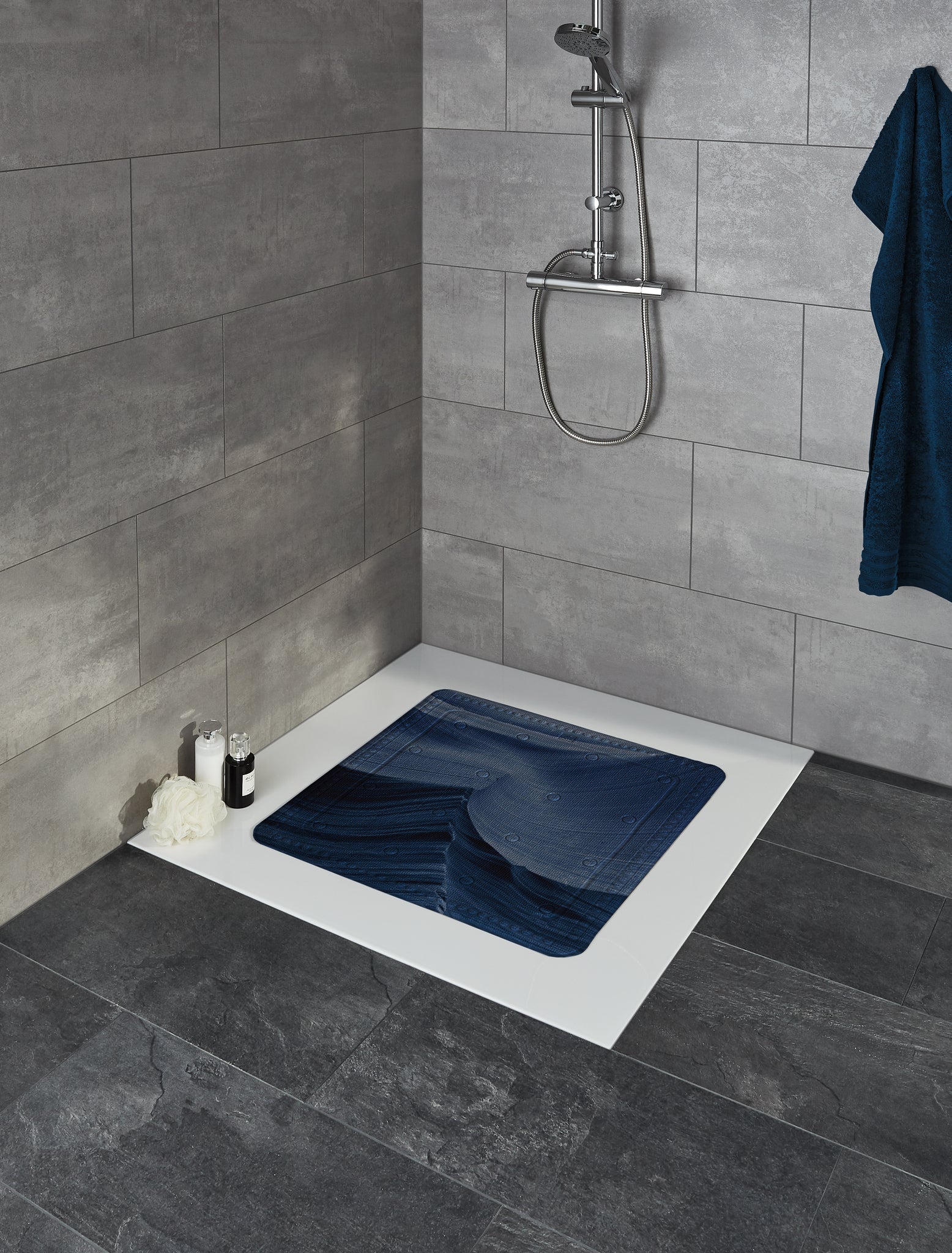 Duscheinlage MYSTIC Navy 55 x 55 cm liegt in moderner Dusche mit grauen Fliesen und Duscharmatur.