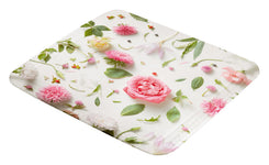 Weiße Badematte mit rosa und grünen Blumenmotiven von oben fotografiert