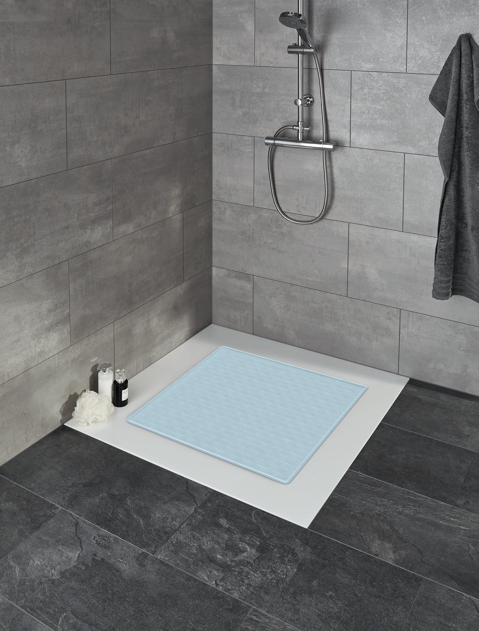 Duscheinlage RUBY Wasserblau 53 x 53 cm liegt in einer modernen, grau gefliesten Dusche mit Ablage.