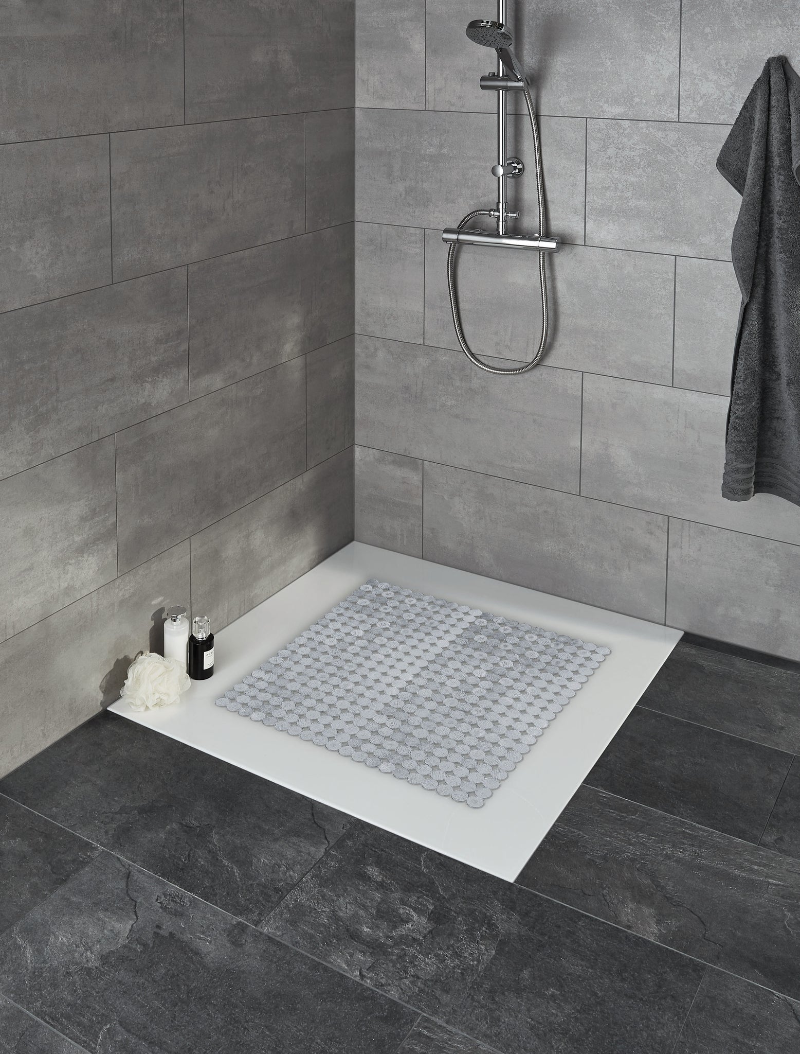 Silberfarbene Duscheinlage SIGN 55 x 55 cm liegt in einer gefliesten Duschtasse mit Duscharmatur.