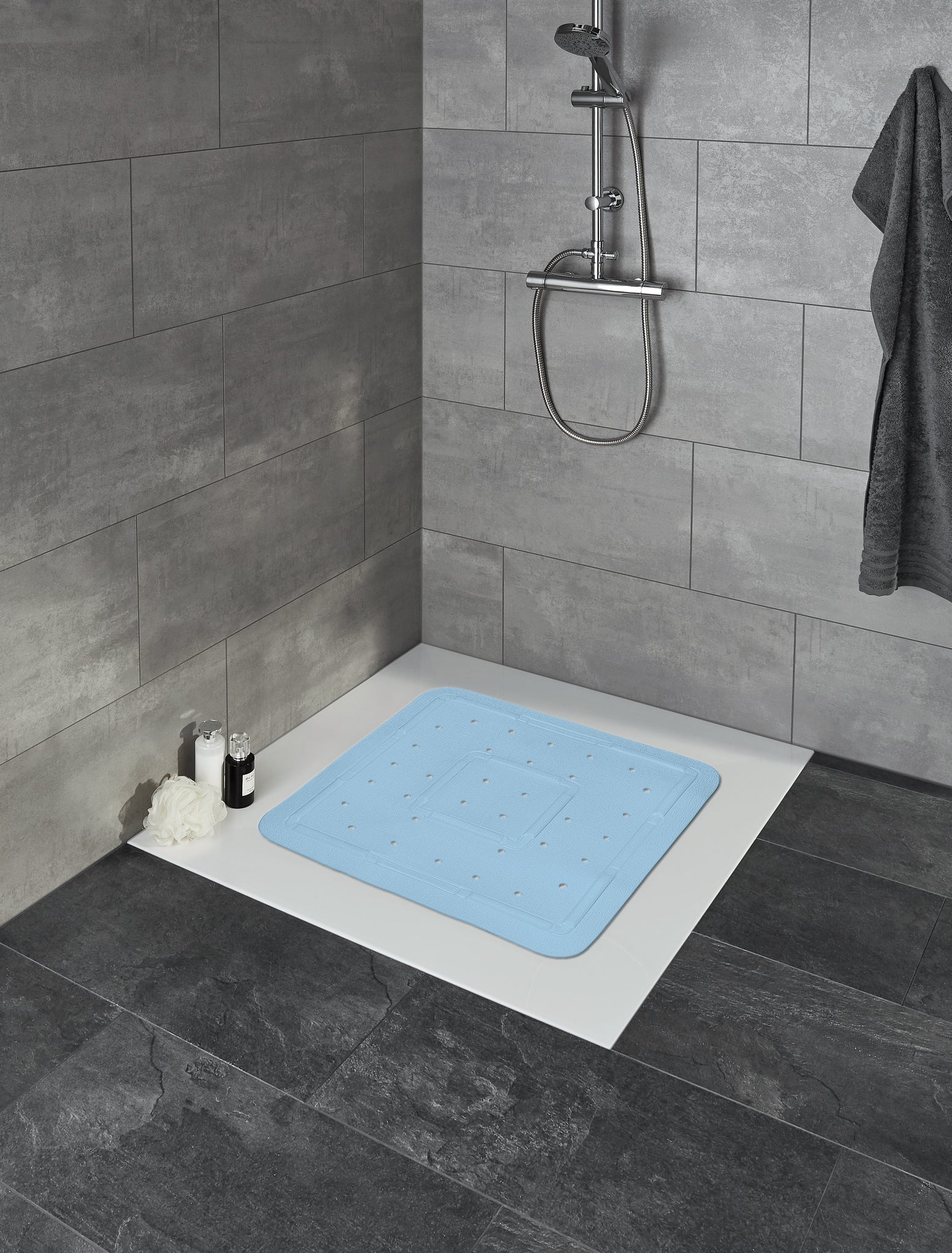 Duscheinlage SOFTY Azur 55 x 55 cm liegt in einer begehbaren Dusche mit grauen Fliesen.
