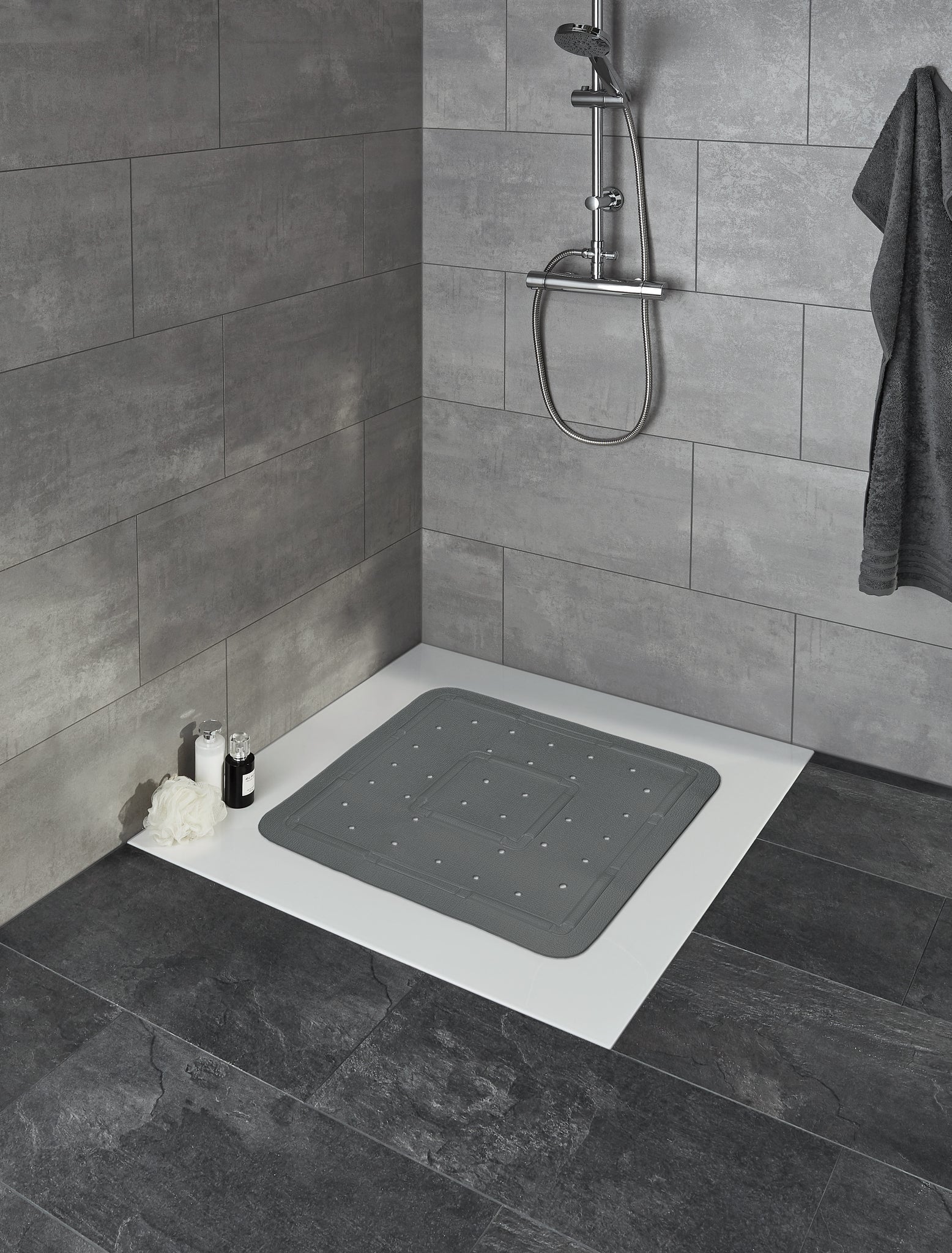 Duscheinlage SOFTY Schiefer 55 x 55 cm liegt auf weißer Duschtasse in grauem Bad.