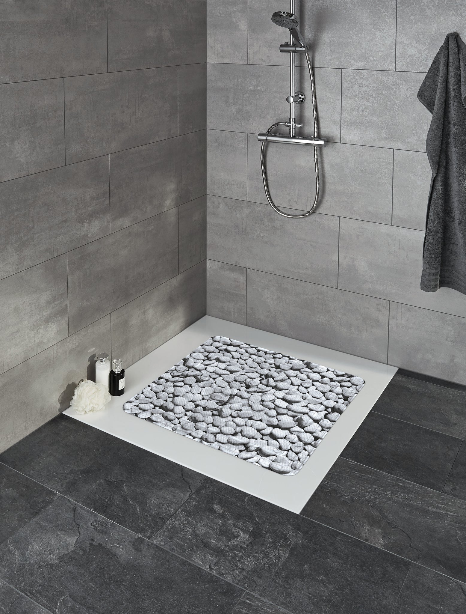 Duscheinlage STEPSTONE Grau 55 x 55 cm liegt in einer gefliesten Eckdusche mit Duscharmatur.