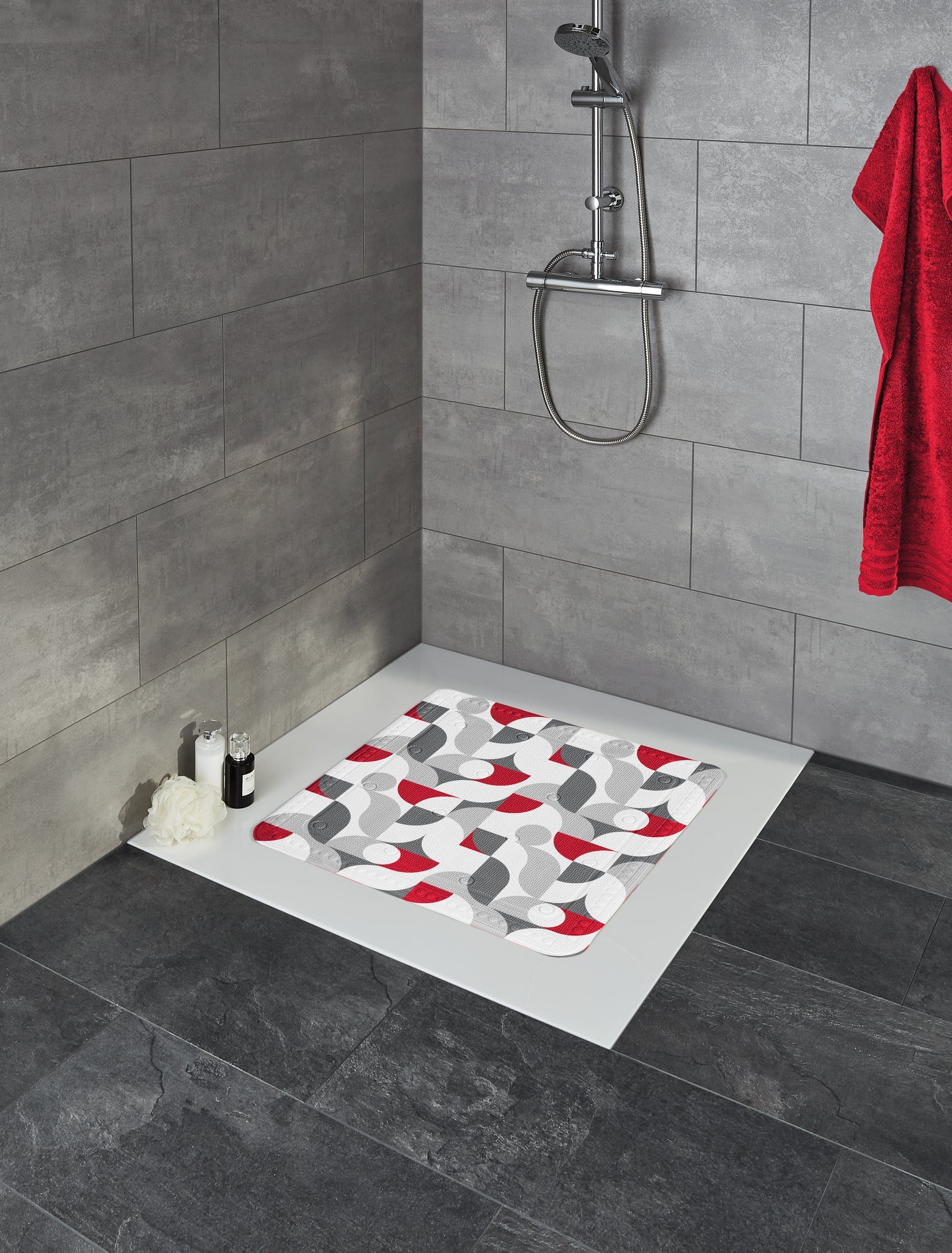 Duscheinlage TESS Rubin 55 x 55 cm liegt in moderner, grauer Dusche mit Handbrause und rotem Handtuch.