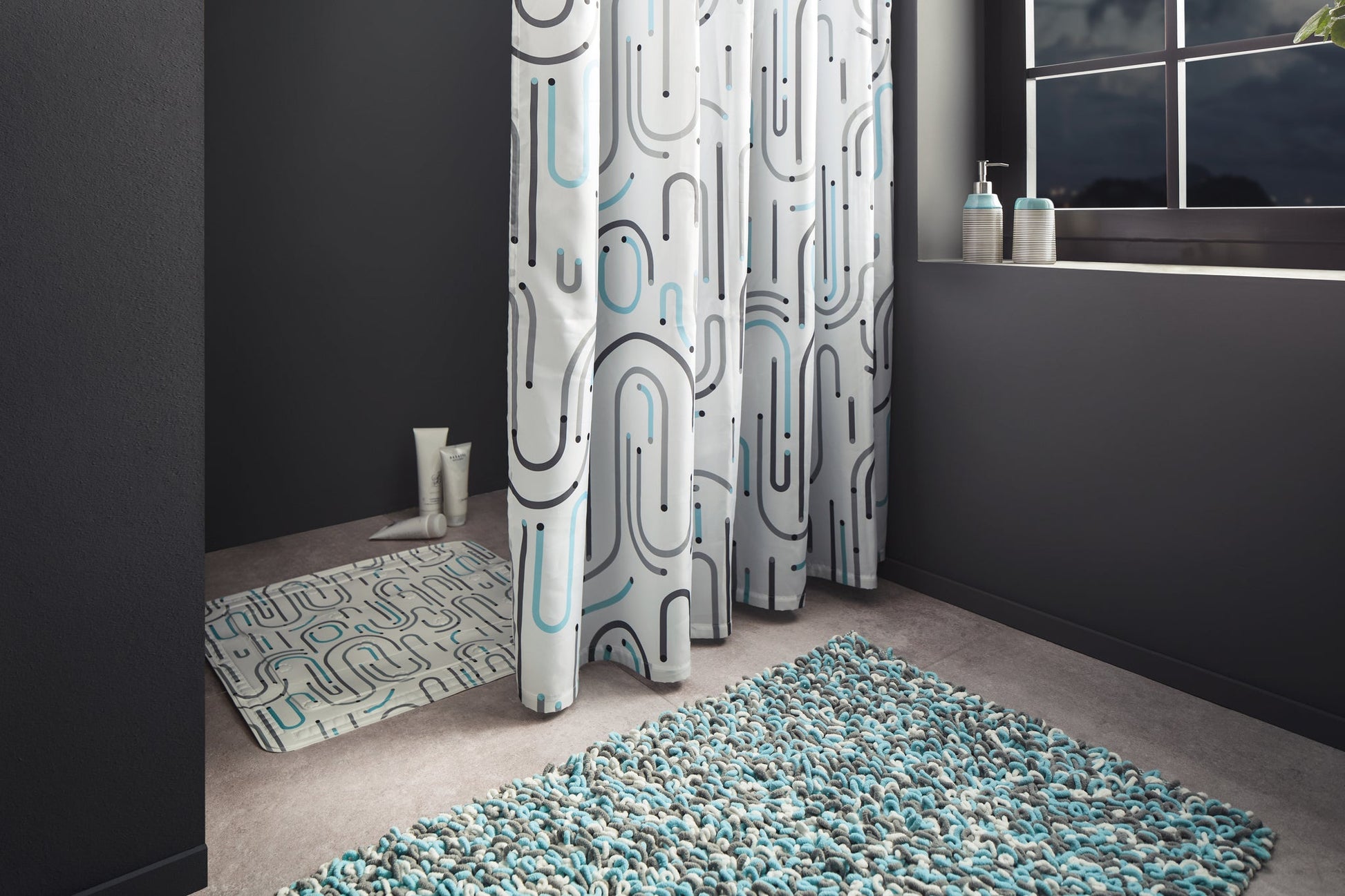 Dusche mit gemustertem Duschvorhang, Badematte und blauer Badteppich