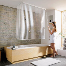 Frau nutzt Duschrollo neben Badewanne im modernen Bad.