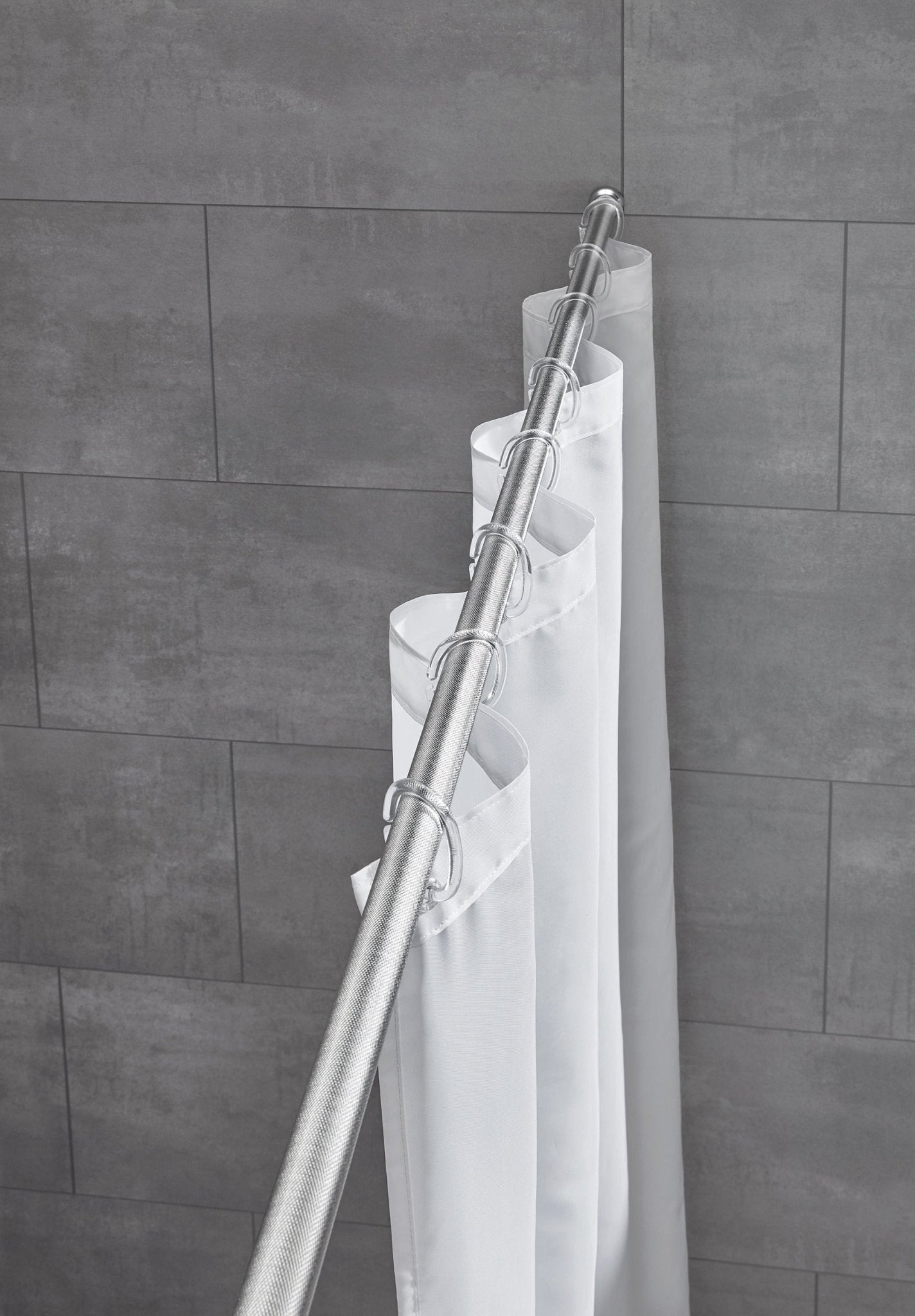 Weißer Duschvorhang an zwei silbernen Duschstangen vor grauen Fliesen