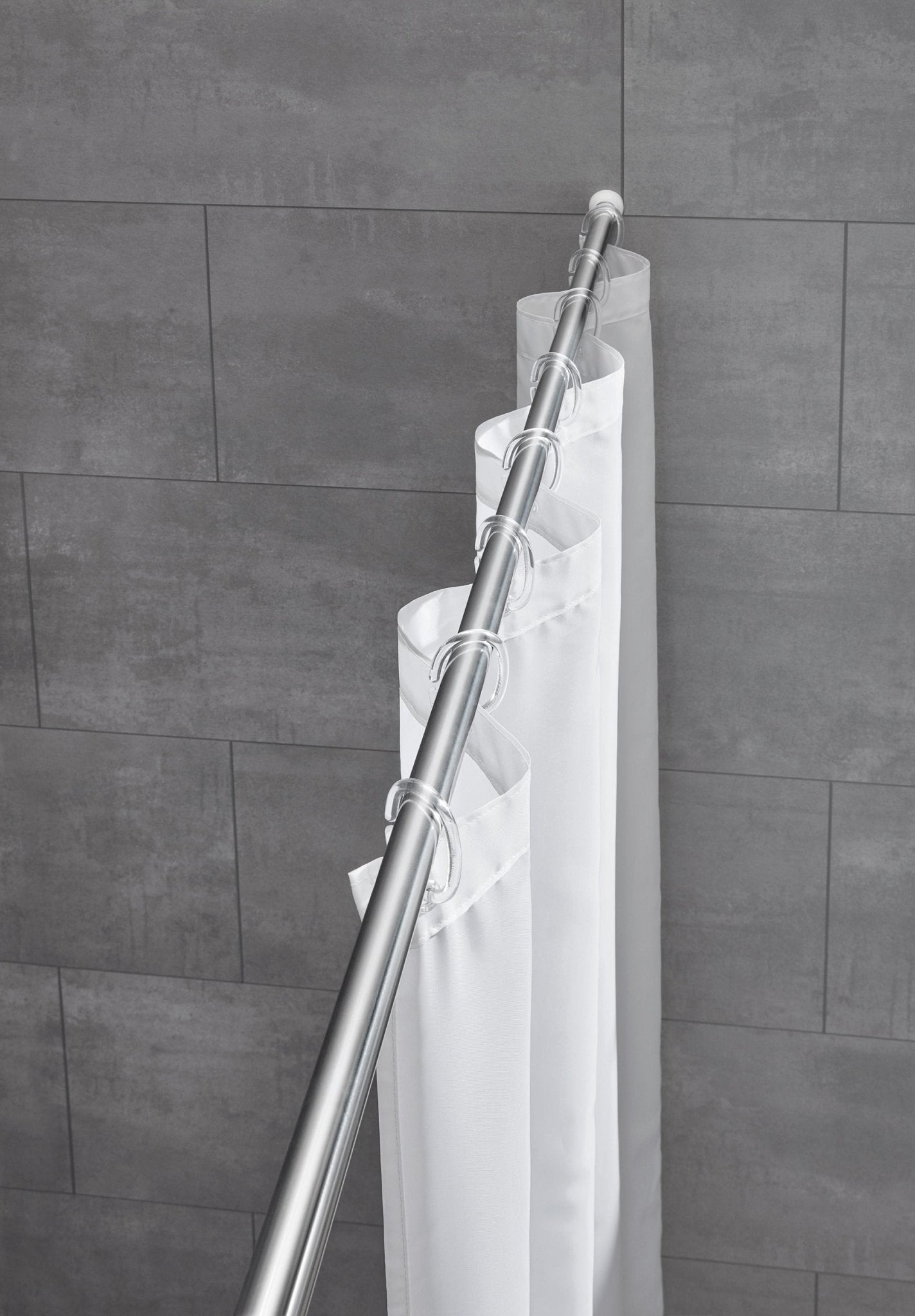 Chromfarbene Duschvorhang-Federstange ⌀ 25 mm mit weißem Duschvorhang vor grauer Fliesenwand.