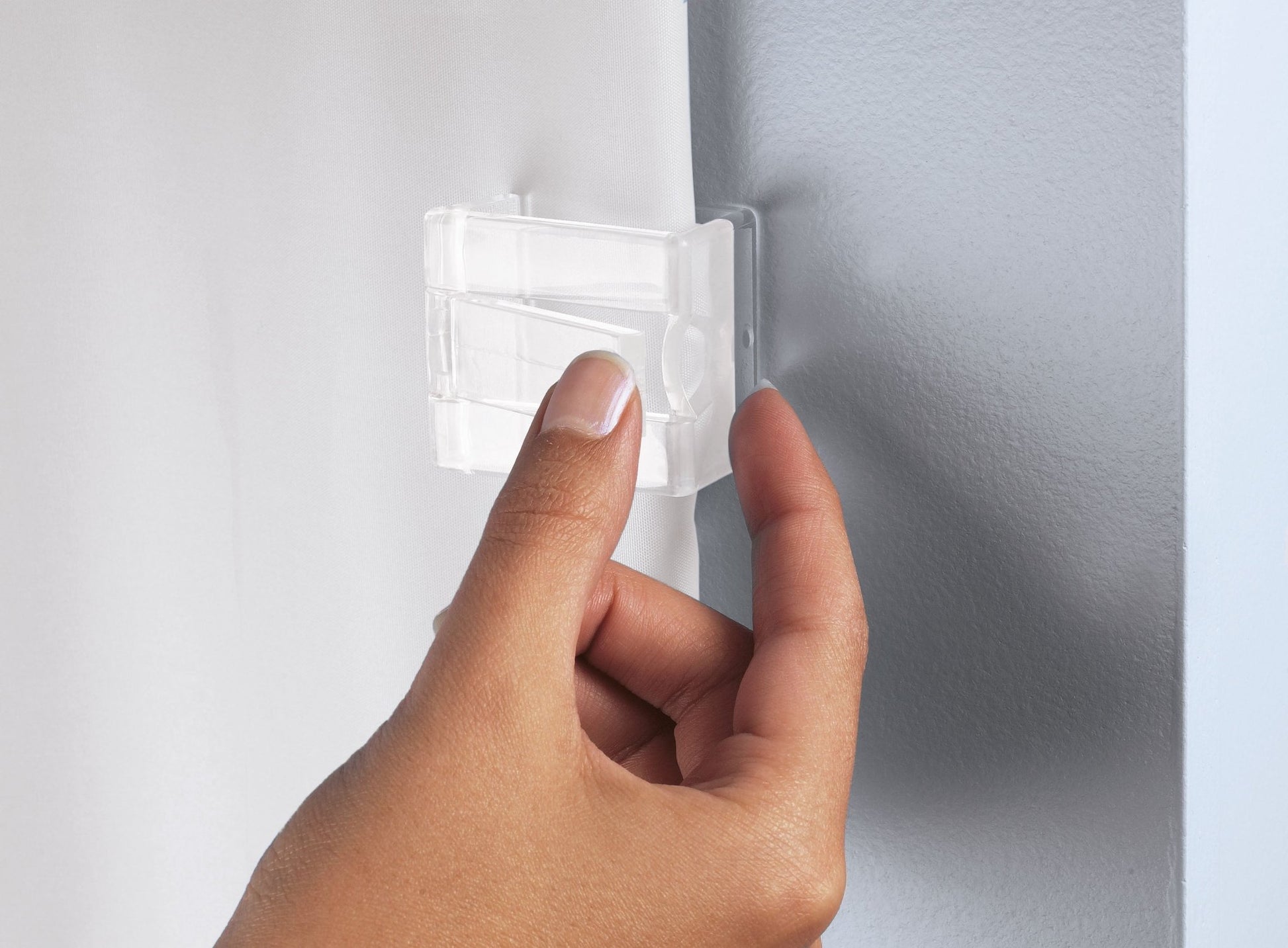 Hand befestigt transparenten Duschvorhang-Clip an heller Wandfläche
