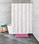 Weiße Badewanne mit buntem Duschvorhang und rosa Badematte auf grauem Fliesenboden