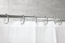 Weißer Duschvorhang an verchromter Stange mit Metallringen vor Fliesenwand