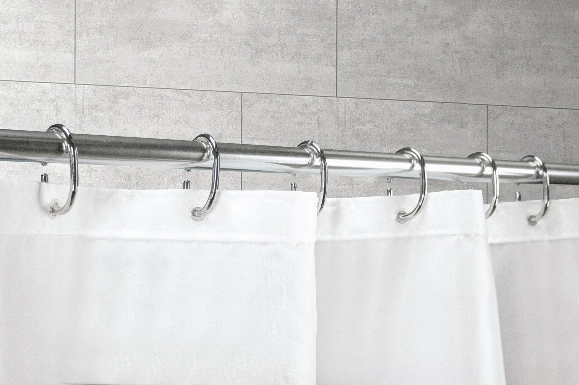 Silberfarbene Duschvorhang-Ringe im 12-teiligen Set halten einen weißen Duschvorhang an der Stange.