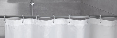 Weißer Duschvorhang an silberner Stange vor grauen Fliesen im Bad