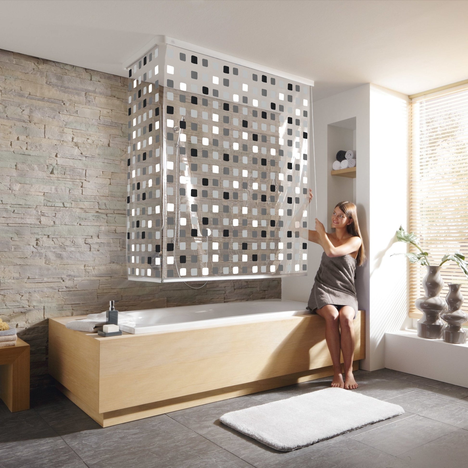 Frau sitzt in moderner Badewanne und zieht graues Eckduschrollo-Komplettset 138 x 240 cm zu.