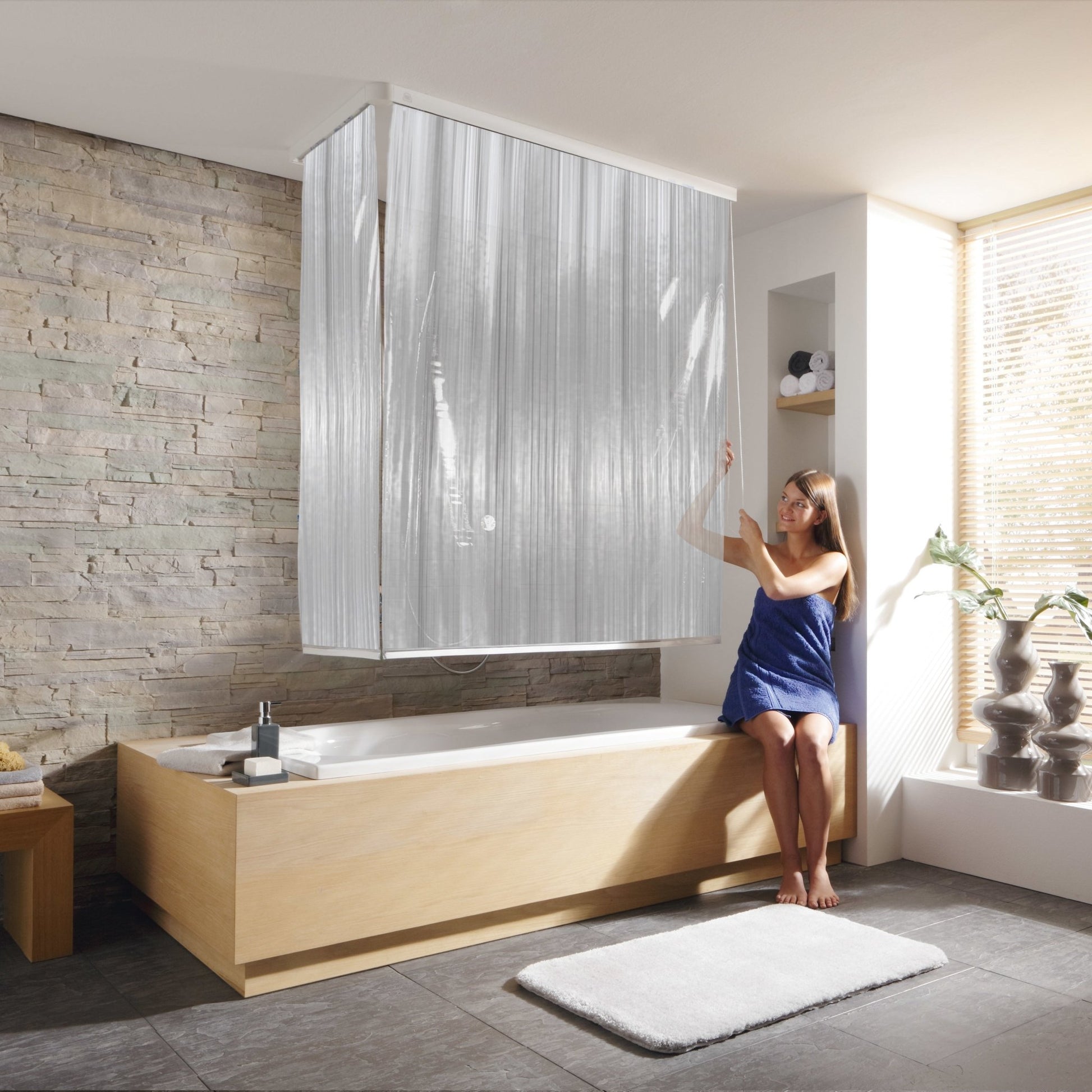 Frau zieht Eckduschrollo-Komplettset Milky an Badewanne in modernem Bad nach oben.