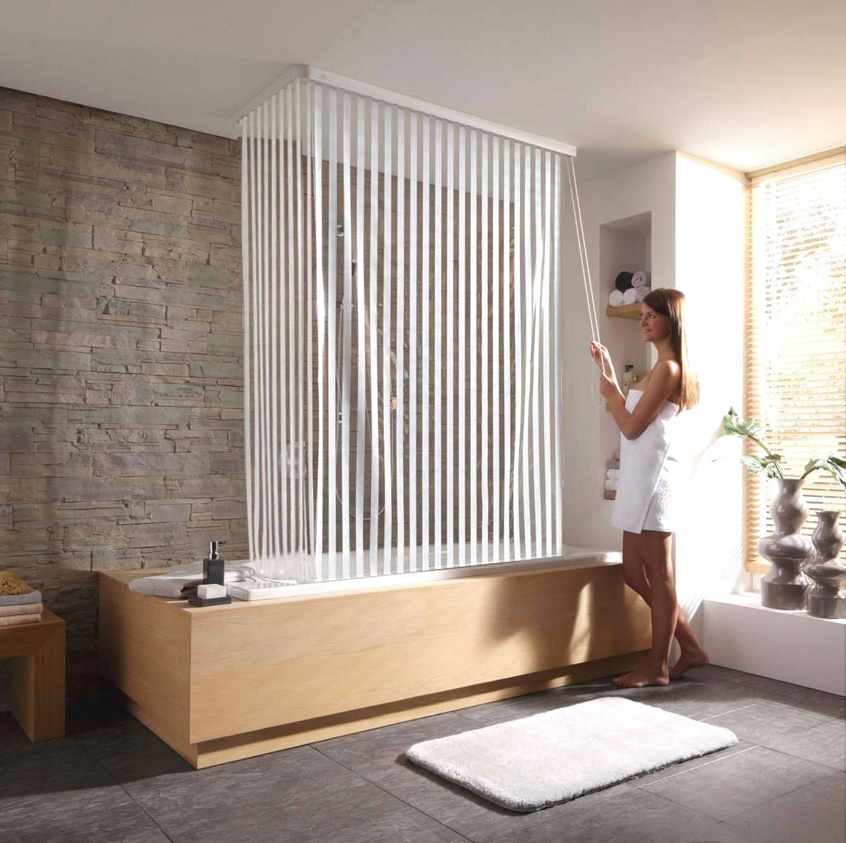 Frau nutzt weißes Eckduschrollo-Komplettset an Badewanne im modernen Bad.