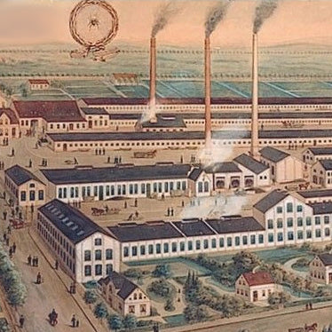 Historische Fabrikanlage mit rauchenden Schornsteinen und umliegenden Gebäuden.