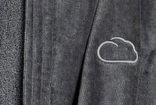 Dunkelgrauer Bademantel mit eingestickter Wolke neben Handtuch aus Frottee