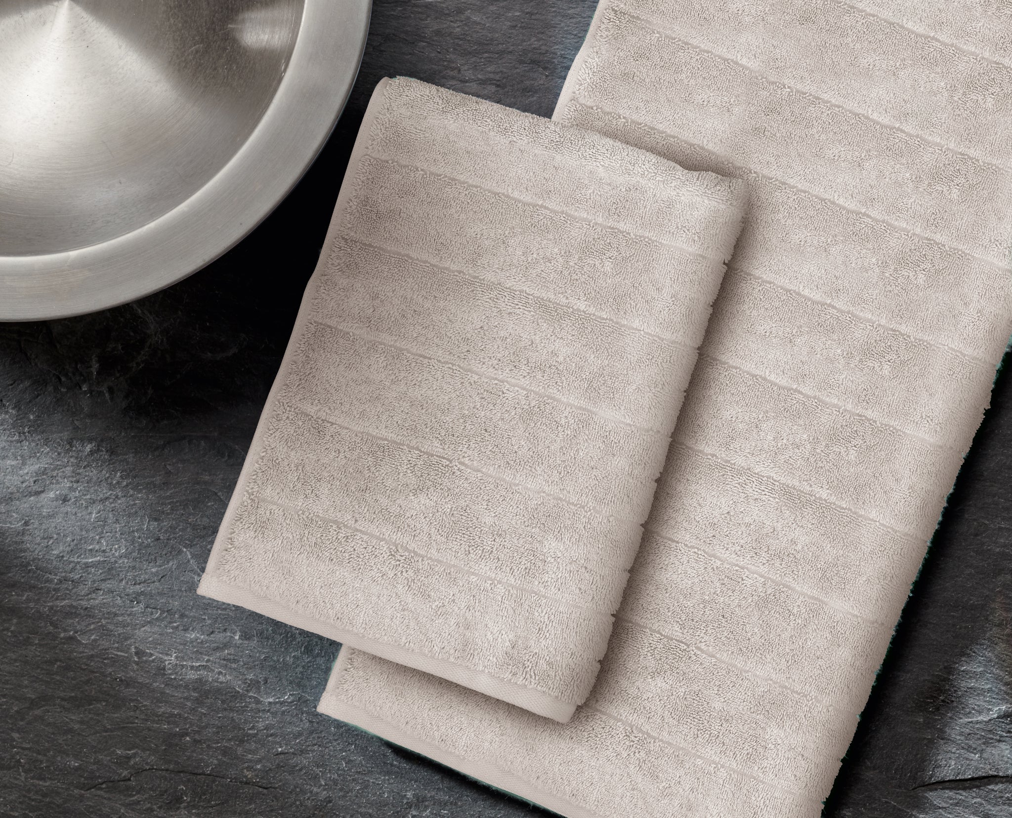 Zwei beige gestreifte Handtücher auf dunkler Steinoberfläche