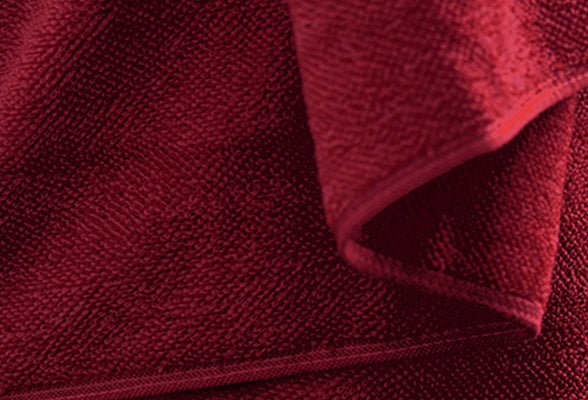 Rubinrote Frottierhandtücher CHILL liegen gefaltet und zeigen die weiche Struktur.