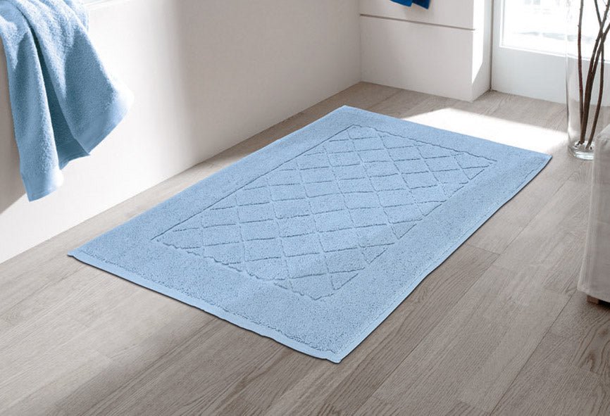 Hellblaue Badematte mit Rautenstruktur auf hellem Badezimmerboden