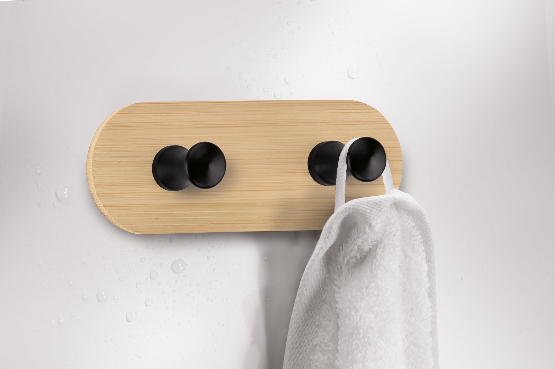 Handtuch an moderner Handtuchhalterung aus Holz mit vier schwarzen Haken