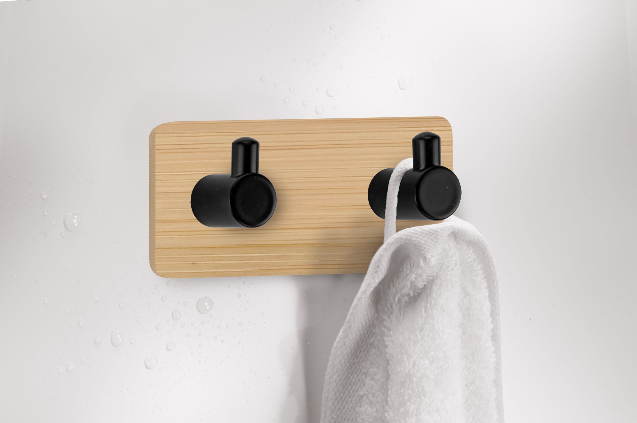 Handtuchhalter aus Holz mit zwei schwarzen Haken und weißem Handtuch