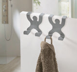 Zwei silberne Handtuchhaken in Menschenform mit braunem Handtuch