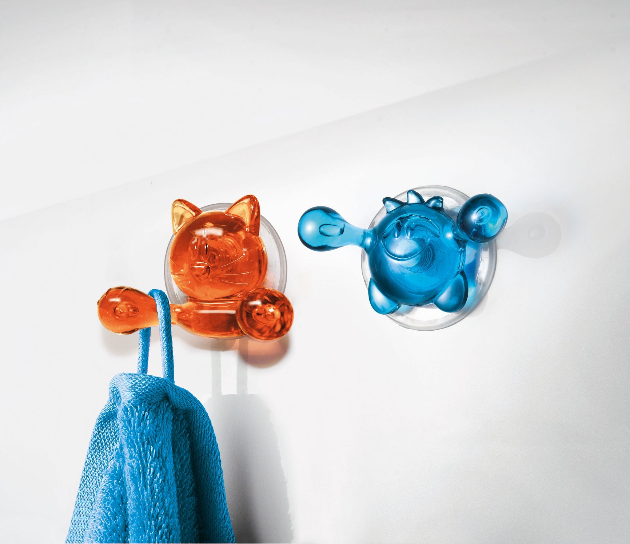 Orange und blauer Saugnapfhaken halten blaues Handtuch an Wand