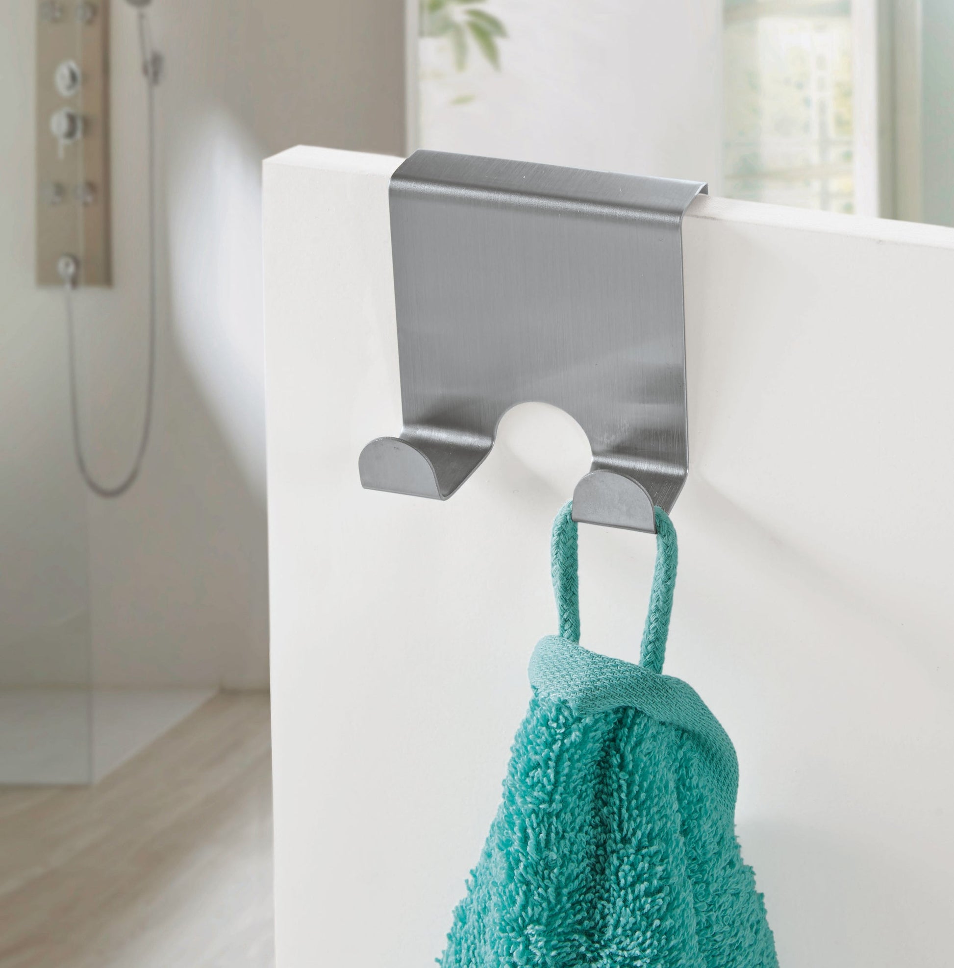 Edelstahl-Handtuchhaken über weißer Duschwand mit türkis Handtuch