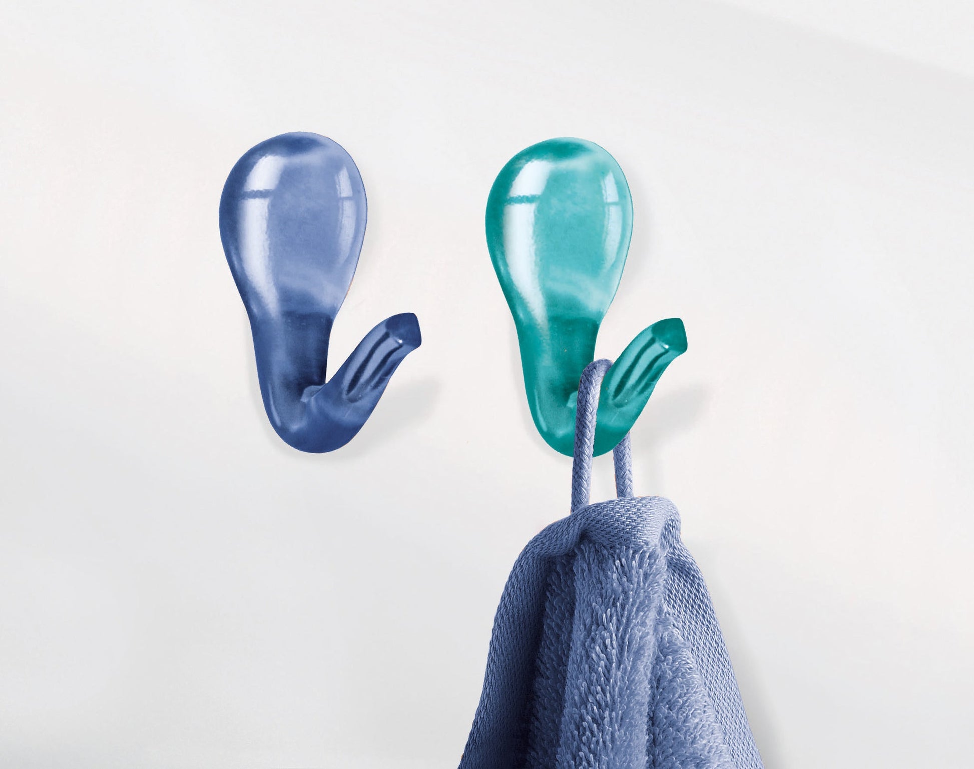 Zwei bunte Wandhaken im Bad, einer mit blauem weichem Handtuch daran
