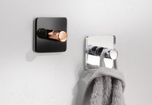 Zwei quadratische Wandhaken, einer mit grauem Handtuch behängt aus Metall