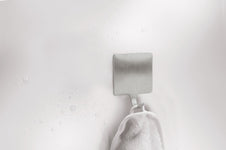 Edelstahl-Handtuchhaken an weißer Wand mit weißem Handtuch unten