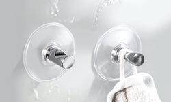 Zwei transparente Wandhaken mit verchromten Knöpfen, einer mit Handtuch