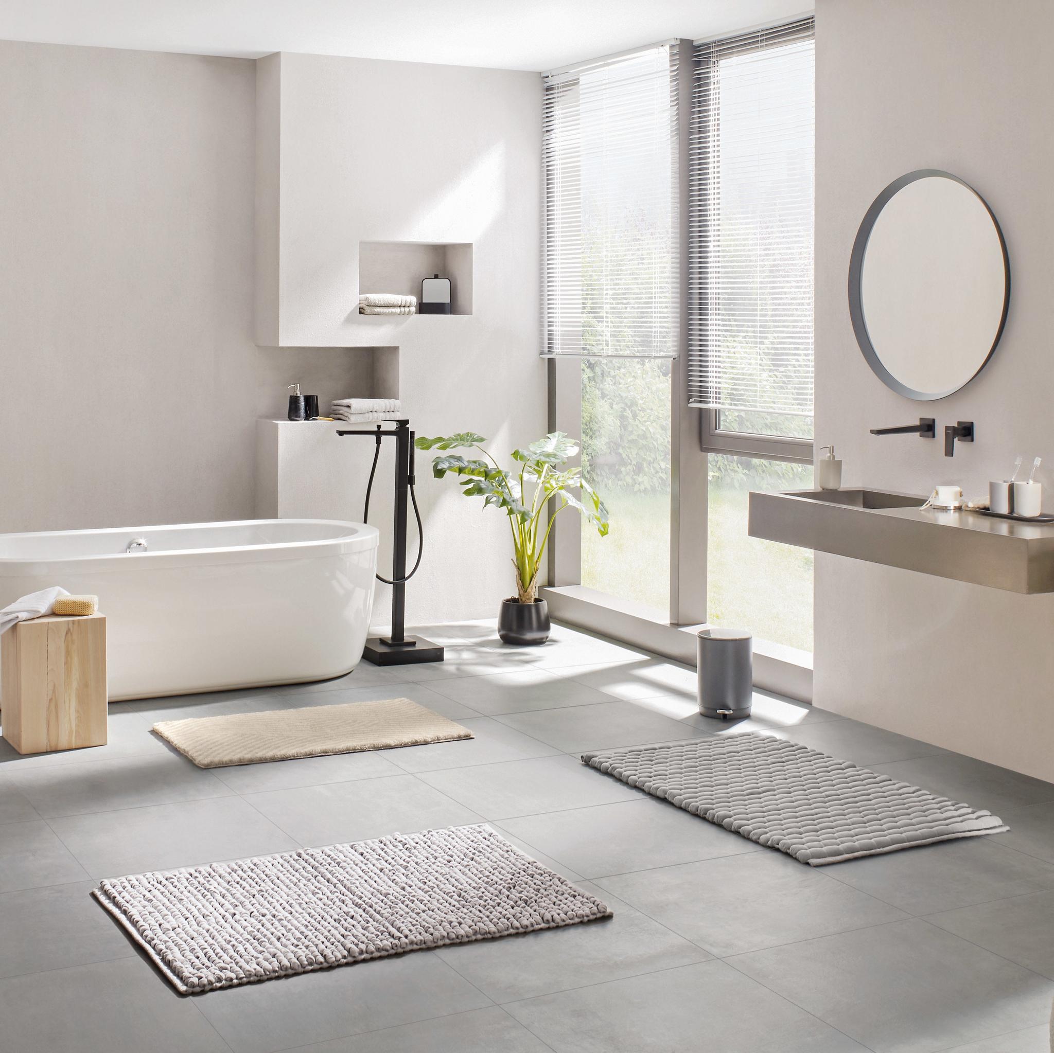 Modernes, helles Bad mit freistehender Wanne und drei Badematten auf Boden