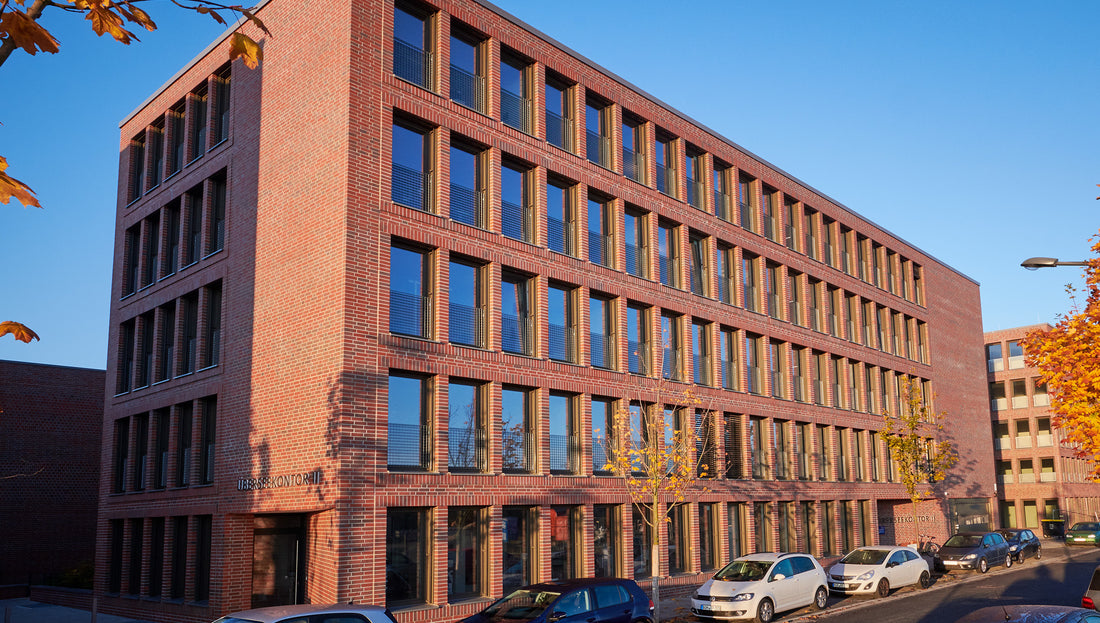 Backsteinbürogebäude der Kleine Wolke Hauptverwaltung mit geparkten Autos bei Sonnenschein.
