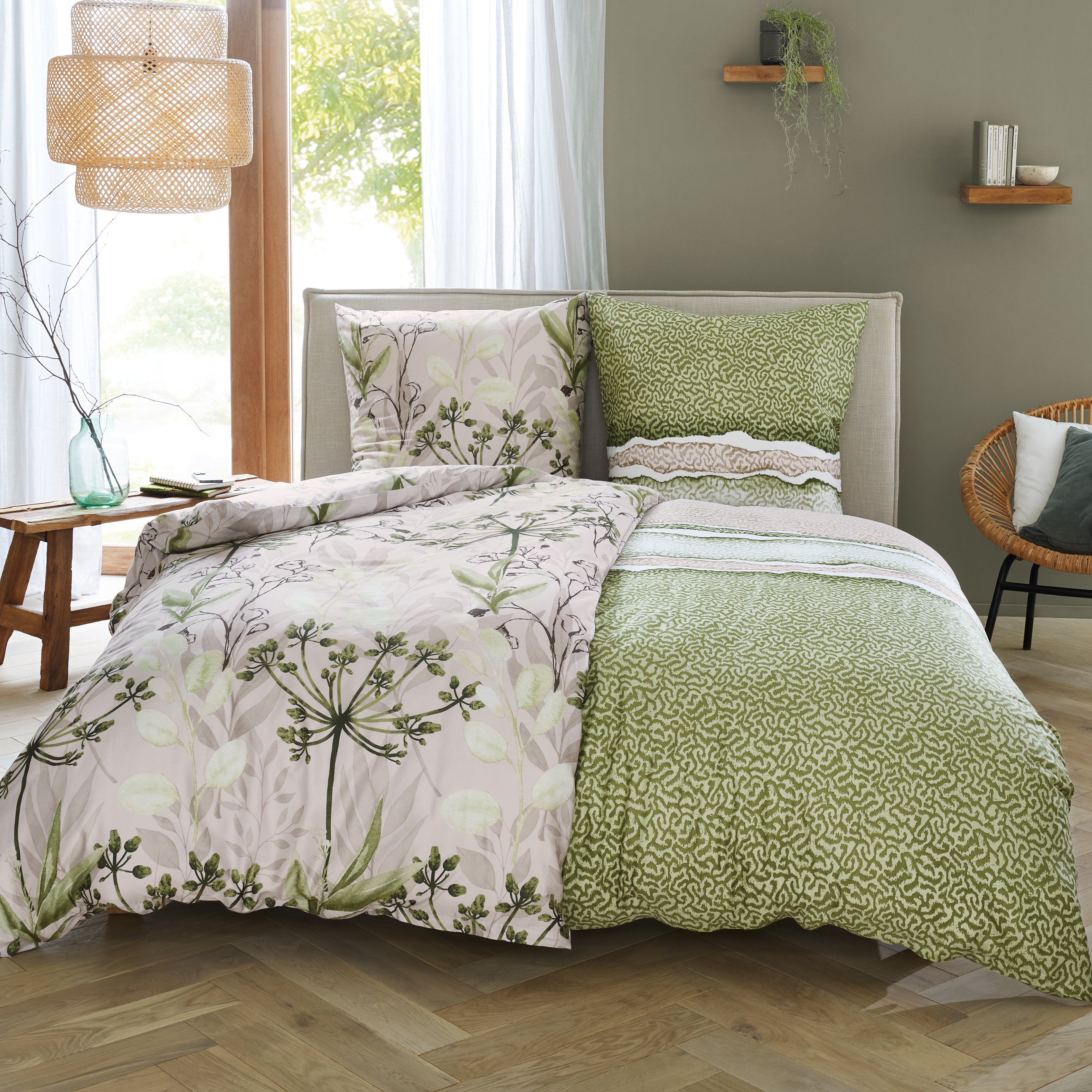 Gemusterte Bettwäsche in Grün und Beige liegt auf einem modern eingerichteten Bett im Schlafzimmer.