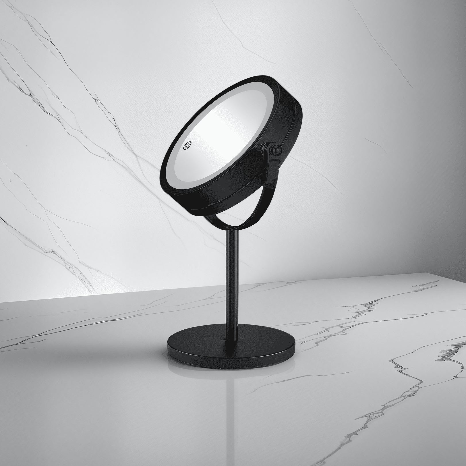 Schwarzer runder Kosmetikspiegel auf Standfuß steht auf marmoriertem Badablageboden.