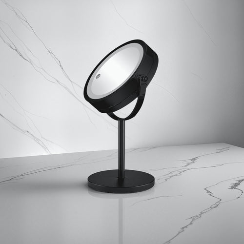 Schwarzer runder Kosmetikspiegel auf Standfuß steht auf marmoriertem Badablageboden.